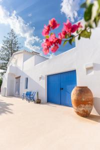 a white building with blue garage doors and pink flowers at Boho Suites Denia in Denia