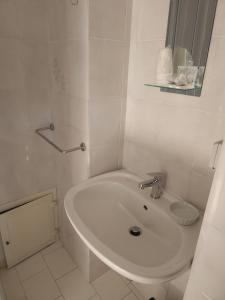 uma casa de banho branca com um lavatório e um espelho em Maison Olimpo em Trani