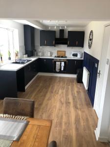 a kitchen with black cabinets and a wooden floor at Lovely detached Cottage, Flint in Flint