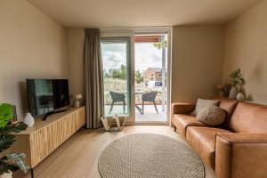 uma sala de estar com um sofá e uma televisão em VlieMare Appartementen De Kluut em Oost-Vlieland