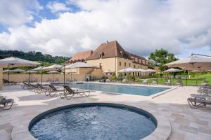 een zwembad met stoelen en parasols en een gebouw bij Hotel Le Perigord in La Roque-Gageac