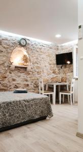 1 dormitorio con pared de piedra, cama y reloj en Falcons Nest, en Šibenik