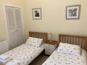 une chambre avec deux lits et une table de chevet avec dans l'établissement Old Station House - Kilfillan Cottage, à Garlieston