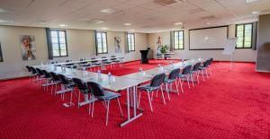 een vergaderzaal met een lange tafel en stoelen op een rode loper bij Hotel Le Perigord in La Roque-Gageac