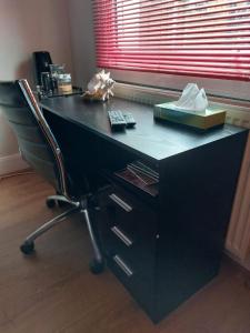 a black desk with a chair in front of a window at White Hart Lane walking distance Tottenham Hotspur Stadium in London