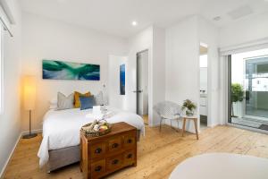 een witte slaapkamer met een bed en een tafel bij Eastern Beach Retreat in Geelong
