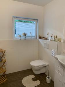 a white bathroom with a toilet and a window at Ferienwohnung KaRo in Bodensdorf