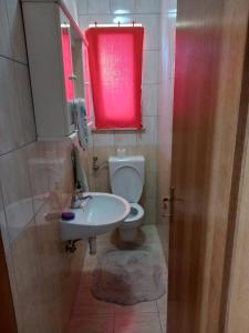 a bathroom with a sink and a toilet with a red window at Apartman MN in Čapljina