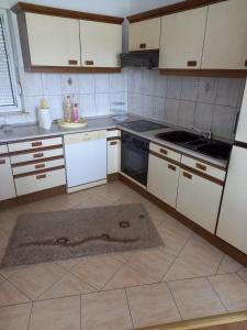 a kitchen with white appliances and a rug on the floor at Apartman MN in Čapljina