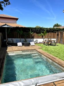 una piscina en un patio con mesa y sillas en Logement avec piscine privée chauffée, en Biarritz