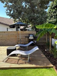 2 chaises et un parasol sur une terrasse en bois dans l'établissement Logement avec piscine privée chauffée, à Biarritz
