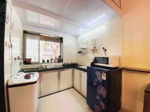 a small kitchen with a sink and a microwave at Bandra Studio Lokhandwala House, Near Carter Road, Palli Hill by Connekt Homes in Mumbai