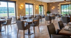 a restaurant with tables and chairs and windows at Hotel Le Perigord in La Roque-Gageac