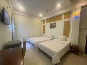 a hotel room with two beds and a flat screen tv at Ly Ky Hotel in Quy Nhon