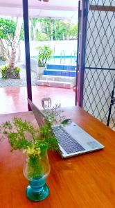 a laptop on a wooden table with a vase with flowers at Calm Villa Wadduwa in Wadduwa