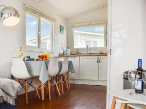 a kitchen with white cabinets and a table with chairs at Bows Pad in Gwithian