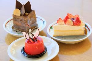 three plates of desserts on a wooden table at Hotel Danrokan in Kofu