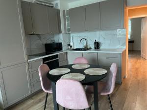a kitchen with a black table and pink chairs at Apartament 30 in Płock