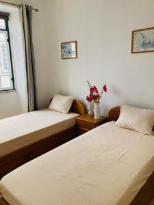 a bedroom with two beds and a vase of flowers at Downtown Apartment in Horta