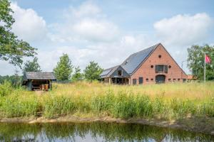 a barn and a house in a field next to a river at Het Heerengoedt in Ambt Delden