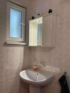 baño con lavabo, espejo y ventana en Mira Home en Veliko Tŭrnovo