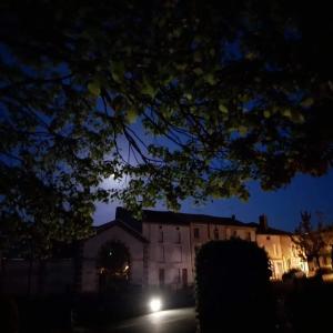 a building at night with a tree in the foreground at Chambres d'Hôtes Bienvenue in LʼAbsie