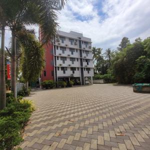 un gran edificio blanco con palmeras delante en Four Squares Inn, Technopark phase 3, en Trivandrum