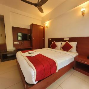 1 dormitorio con 1 cama grande con manta roja en Four Squares Inn, Technopark phase 3, en Trivandrum