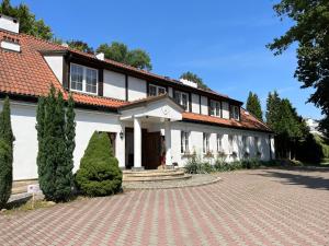 a white house with a brick driveway in front of it at Dedek Park - historyczny dworek w pięknym Parku Skaryszewskim obok Stadionu Narodowego in Warsaw