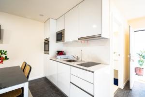 a kitchen with white cabinets and a table at Casa da Bina in Paredes