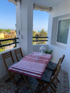 una mesa y sillas en un balcón con ventana en Piso muy moderno para 4 personas y una cuna a 7 min caminando a la playa, con aire, balcón con vistas y 2 piscinas, en El Puerto de Santa María