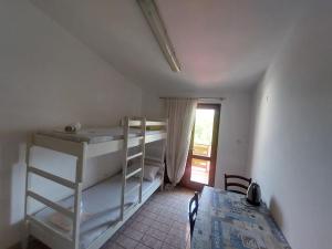 a room with two bunk beds and a table and a window at Studio-app Iva, balcony with sea view - 50 m from beach in Pag