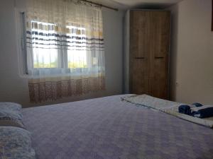 ein Schlafzimmer mit einem großen Bett und einem Fenster in der Unterkunft Apartments Pekic in Vranjina