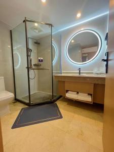 a bathroom with a shower and a sink and a mirror at Chengdu Bai Gang International Hotel in Chengdu