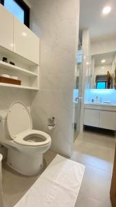 La salle de bains blanche est pourvue d'une douche et de toilettes. dans l'établissement Cozy place @ Chiangrai, à Chiang Rai