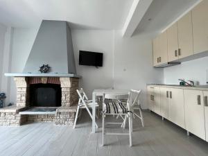 a kitchen with a fireplace and a table and chairs at La Casa Al Mare in Mola Kalyva