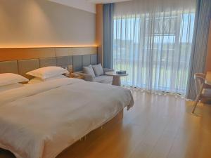 a hotel room with a large bed and a chair at Chengdu Bai Gang International Hotel in Chengdu