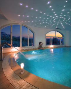 a swimming pool in a house with lights and windows at Hotel La Rocca Resort & Spa in Baja Sardinia