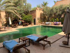a swimming pool with two lounge chairs and an umbrella at Le moulin in Taroudant
