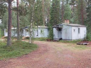 a couple of small white buildings in the woods at Linsell stuga in Linsell