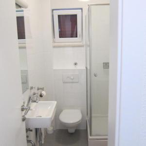 La salle de bains blanche est pourvue de toilettes et d'un lavabo. dans l'établissement Vila Anda, à Promajna