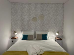 1 dormitorio con 1 cama blanca y 2 toallas en The Pearl of Seixal, en Seixal