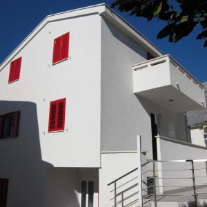 een wit gebouw met rode luiken erop bij Vila Anda in Promajna