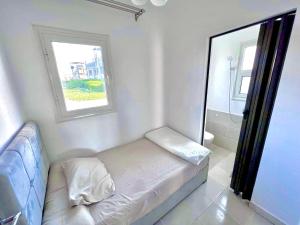 Habitación blanca pequeña con cama y ventana en Your Go-to Place at Amwaj, North Coast for Summer!, en El Alamein