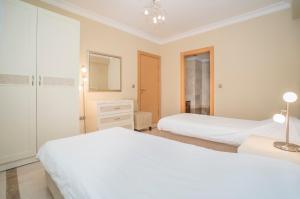 a white bedroom with two beds and a dresser at ALANYA GOLD CİTY in Alanya