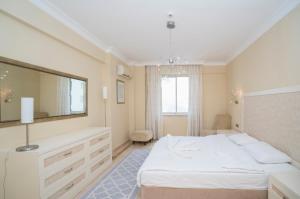 1 dormitorio con cama blanca y espejo grande en ALANYA GOLD CİTY en Alanya