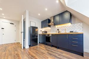 een grote keuken met blauwe kasten en houten vloeren bij 7 - West London Brand New Loft in Londen