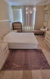Un dormitorio con una gran cama blanca y una lámpara de araña. en ALANYA GOLD CİTY en Alanya