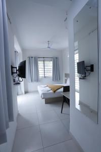 a white room with a bed and a mirror at Hotel Gurudev Residency in Bangalore