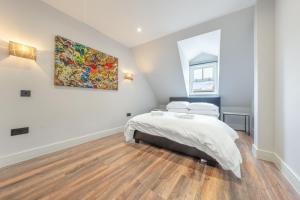 倫敦的住宿－7 - West London Brand New Loft，卧室配有一张床,墙上挂有绘画作品